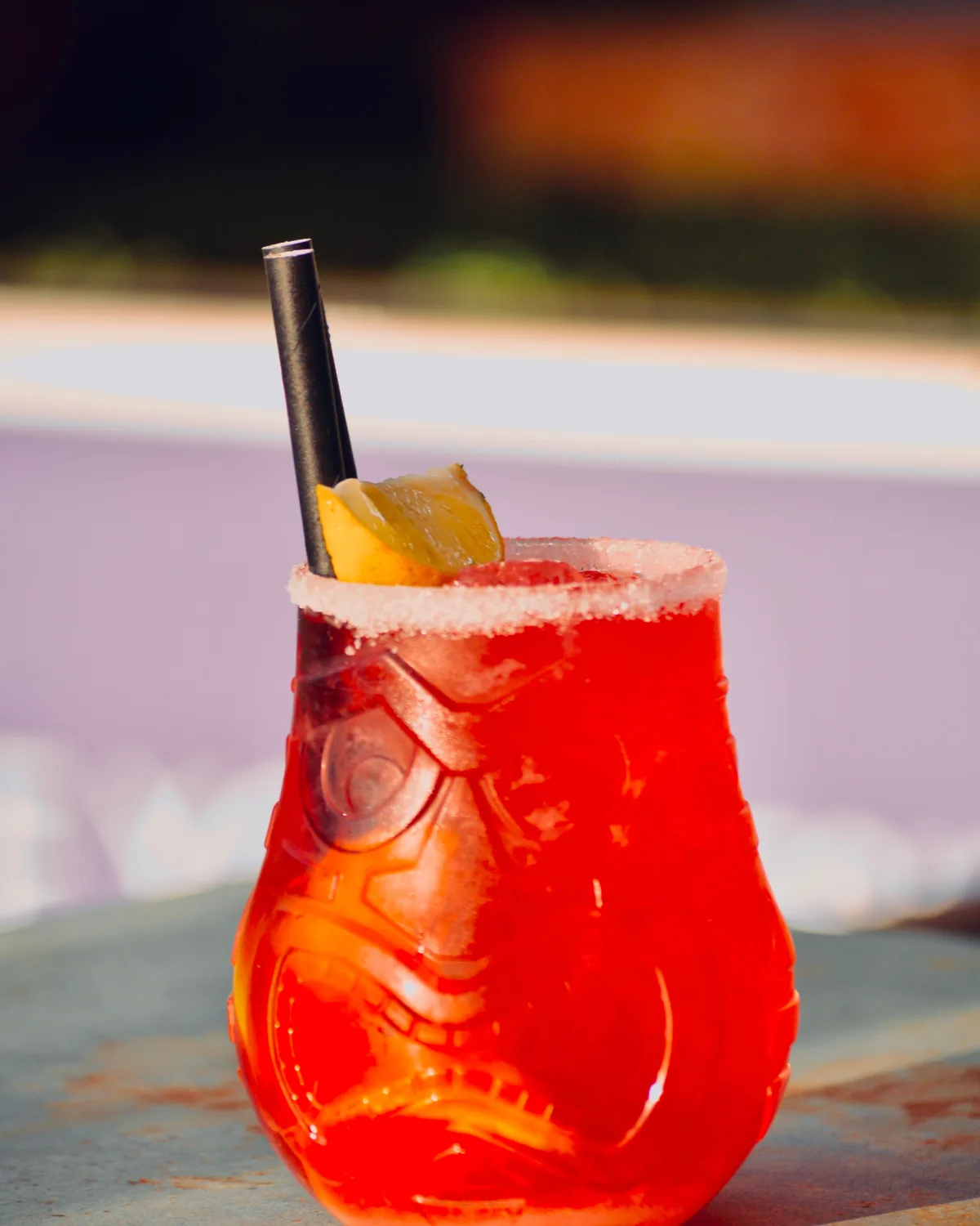 A bright red tropical cocktail in a carved tiki glass with a lemon garnish (representative photograph of a tiki bar drink, not the Chief's Luau bar itself)